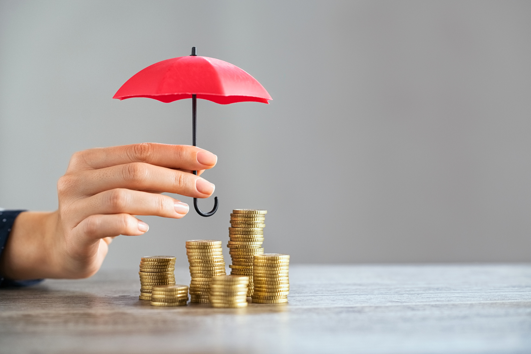 Person's Hand Protecting the Stacked Coins with an Umbrella